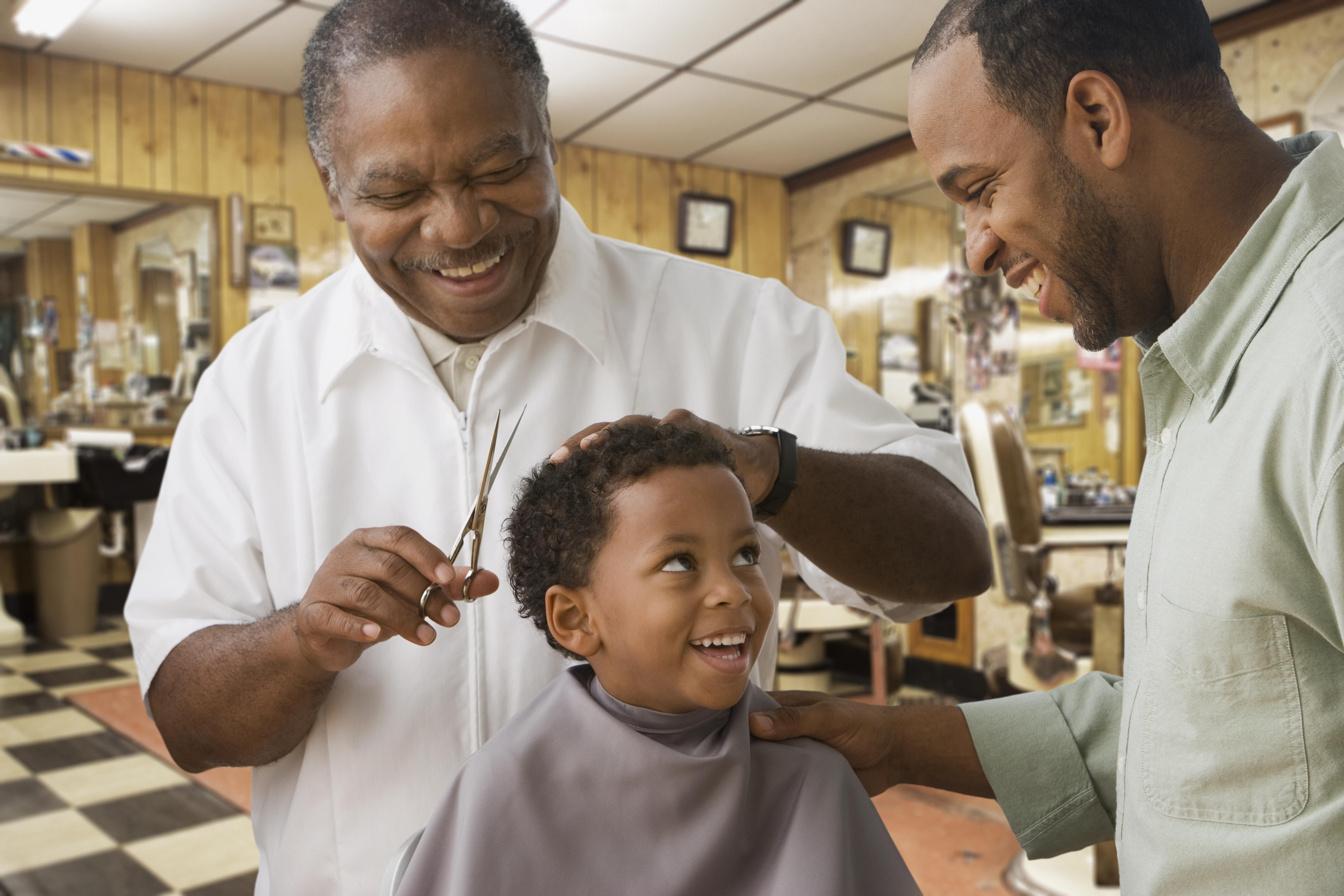 African boy with father getting haircut at barbershop