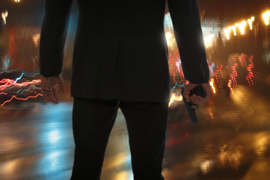 Bodyguard standing with gun during rain at night.