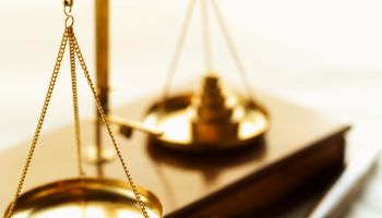 Close-up of weights balancing scales of justice with gavel beside it