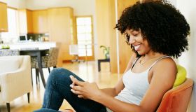 Mixed race woman using cell phone in armchair