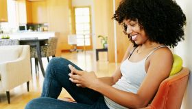 Mixed race woman using cell phone in armchair