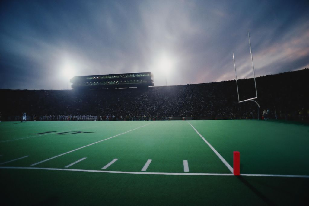 Football stadium filled with spectators during game, twilight