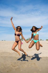 Two women jumping in air at Venice Beach, California