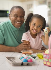African grandfather and granddaughter coloring Easter eggs