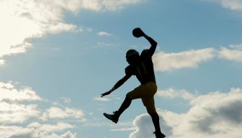 Teenage american football player, jumping with ball, mid air