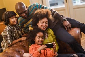 African American family relaxing at home and using cell phone.