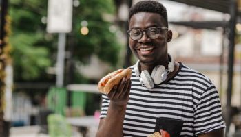 Young African-American man eating hot dog on the go