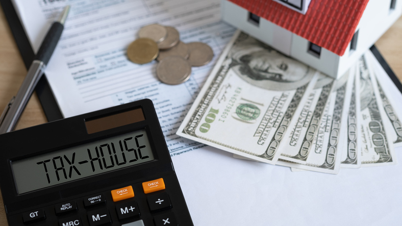 Tax house on calculator and Miniature house with money on tax papers. The concept of paying tax for housing and property. Debt payment. Property taxes. Tax house concept.