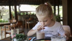 Cute 5 years old girl having chocolate milk and fruit plate at the restaurant