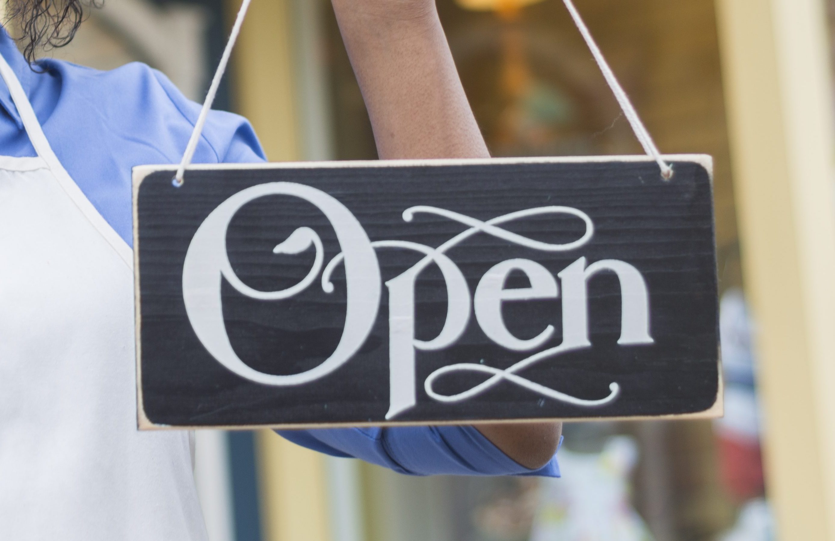 African American woman with apron holding an open sign
